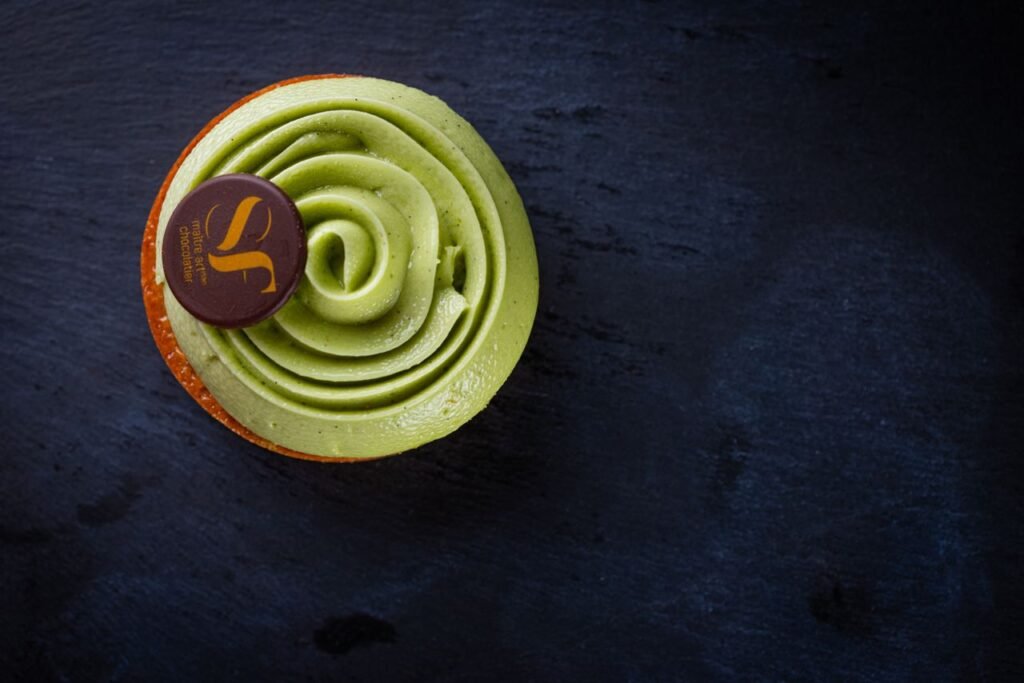 Top-view of a pistachio pastry showcasing elegant design on a dark slate surface.