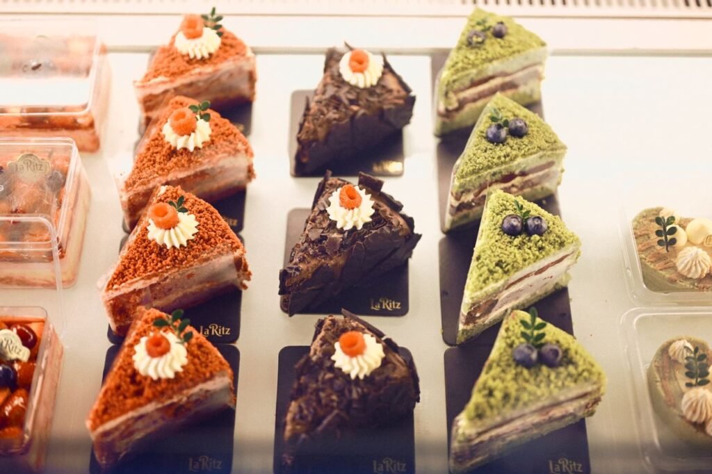 A variety of gourmet cakes are beautifully arranged in a display case, showcasing diverse flavors and decorations.