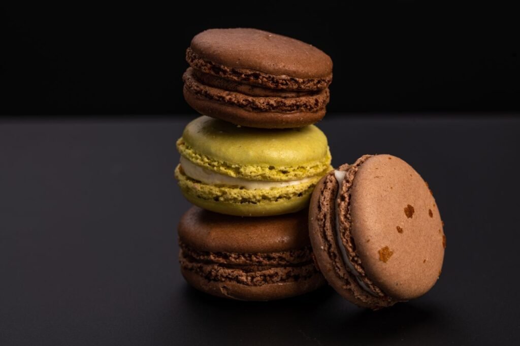 Delicious sweet brown and yellow macaroons arranged on table against black blurred background
