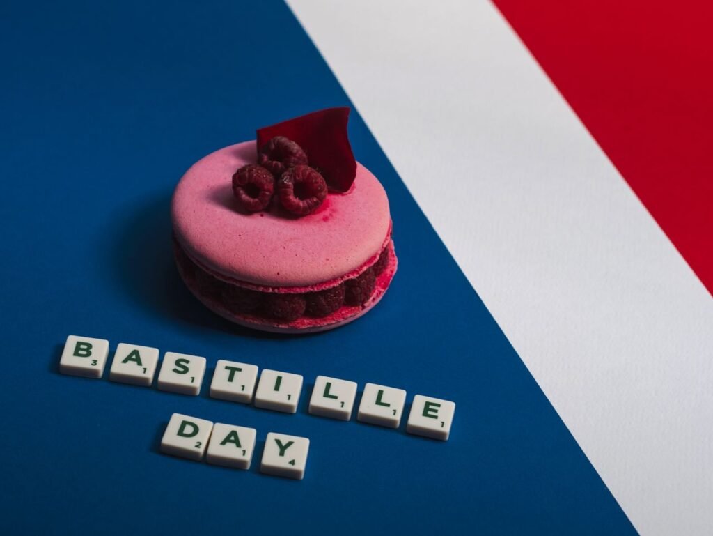 Pink macaron with raspberries on a French flag background, celebrating Bastille Day.